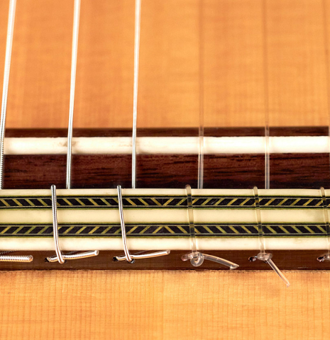 The bridge and saddle of a 2004 Vicente Carrillo &quot;1aF Negra&quot; flamenco guitar made of spruce and padauk