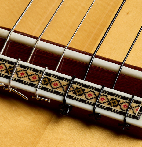 The bridge, saddle and tie-block of a 2025 Vicente Carrillo "1aF Negra" flamenco guitar made of spruce and African rosewood