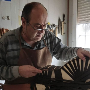 Vicente Carrillo in his workshop, binding the body of a guitar wrapped in tape while the glue sets