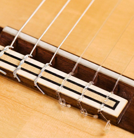 The bridge and saddle of a 2019 Felipe Conde "FP 16" flamenco guitar made of spruce and cypress
