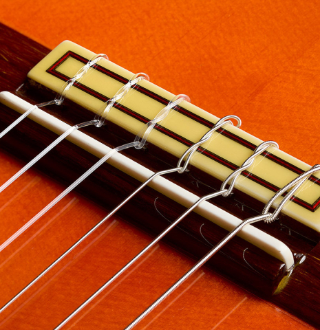 The bridge, tie-block and saddle of a 2016 Felipe Conde "FC 26" flamenco guitar made of spruce and cypress