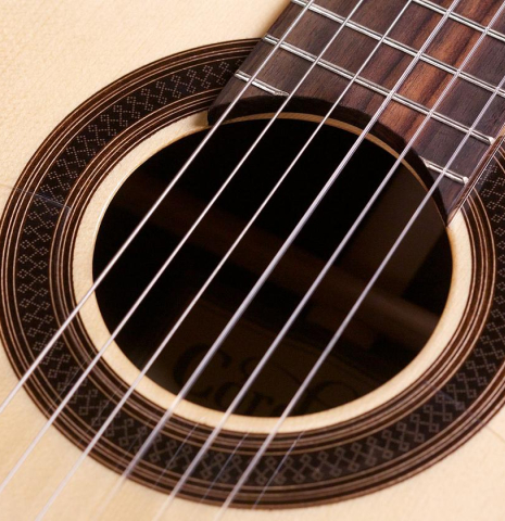 The rosette and nylon strings of a Cordoba &quot;GK Studio Negra&quot; electric/acoustic guitar made of spruce and Indian rosewood
