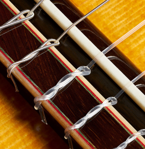 The bridge, tie-block and saddle of a 2018 Luis Fernandez de Cordoba "Blanca" flamenco guitar made of spruce and cypress
