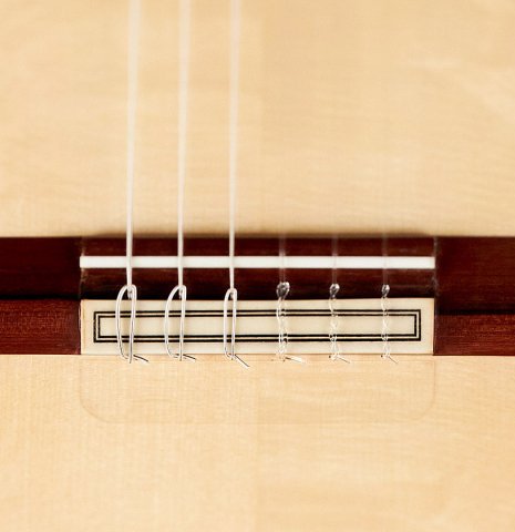The bridge, tie-block and saddle of a 2023 Felipe Conde Crespo "Negra" flamenco guitar made of spruce and koa