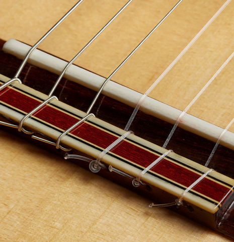 The bridge, tie-block and saddle of a 2012 Andy Culpepper "Coral" flamenco guitar made of spruce and padauk