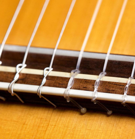 The bridge, nylon strings, and saddle of a 1966 Manuel de la Chica flamenco guitar made of spruce and cypress