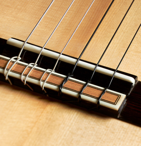 The bridge, tie-block and saddle of a 2023 Paco Fajardo flamenco guitar made of spruce and cypress