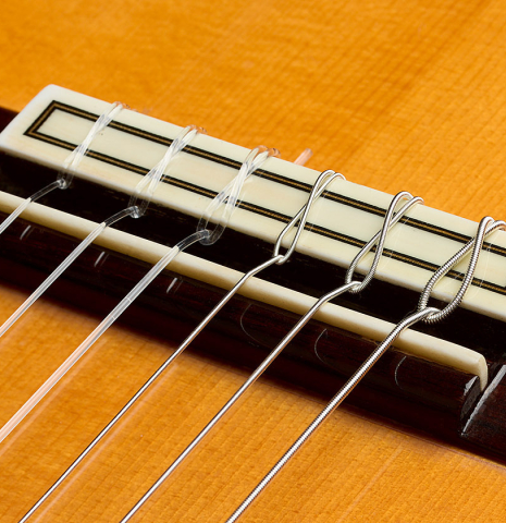 The bridge, tie-block and saddle of a 1999 Gerundino Fernandez w/pegs flamenco guitar made of spruce and cypress