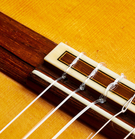 The bridge, tie-block and saddle of a 1961 Arcangel Fernandez flamenco blanca guitar with pegs made of spruce and cypress.