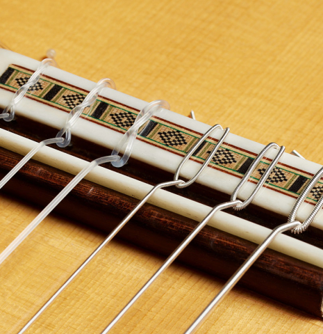 The bridge, tie-block and saddle of a 2024 Dario Garcia flamenco guitar made of spruce and cypress