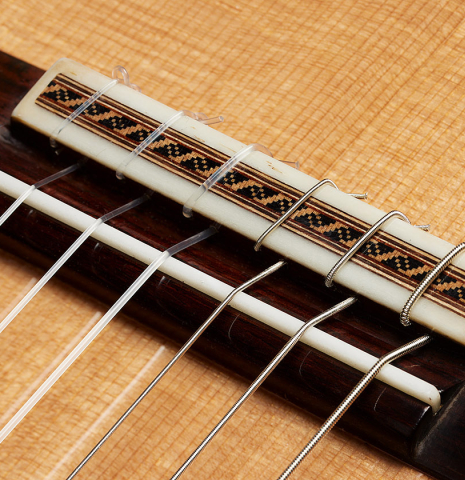 The bridge, tie-block and saddle of a 2025 Darío García "Flamenco Negra" guitar made of spruce and kamagong