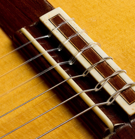 The bridge, tie-block and saddle of a 1998 Gerundino Fernandez flamenco guitar made of spruce and cypress