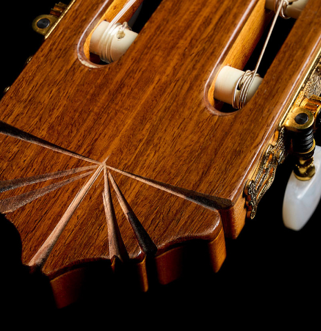 The carved headstock of a 1998 Gerundino Fernandez flamenco guitar made of spruce and cypress