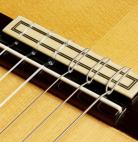 The bridge, tie-block and saddle of a 2008 Conde Hermanos "AF 25/R" flamenco guitar made with spruce and CSA rosewood.