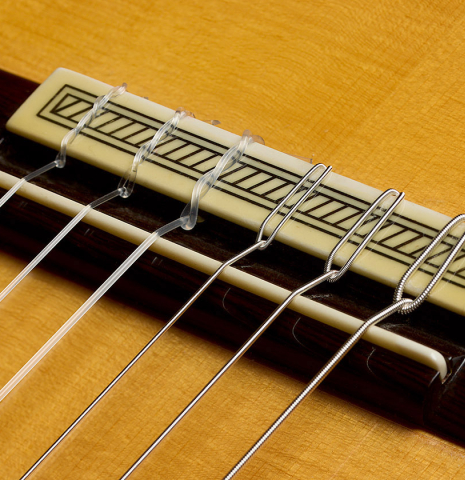 The bridge, tie-block and saddle of a 2006 Conde Hermanos "Felipe V" flamenco guitar made of spruce and cypress