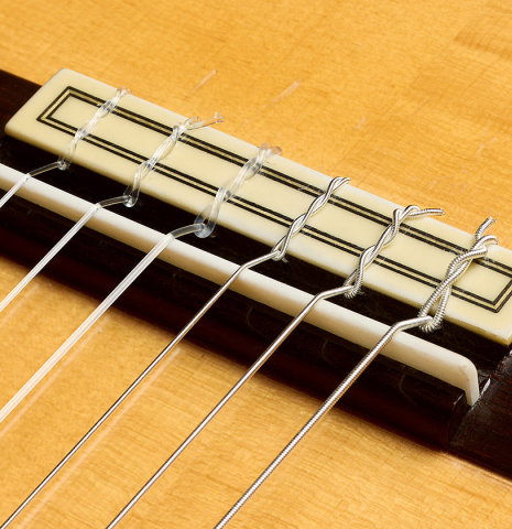 The bridge, tie-block and saddle of a 2001 Conde Hermanos "AF 25/R" flamenco guitar made of spruce and CSA rosewood