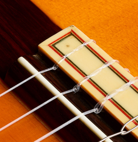 The bridge, tie-block and saddle of a 1987 Conde Hermanos "Negra" flamenco guitar made of spruce and Indian rosewood