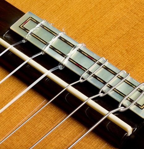The bridge, tie-block and saddle of a 2001 Conde Hermanos "Felipe V" flamenco negra guitar made of cedar and CSA rosewood