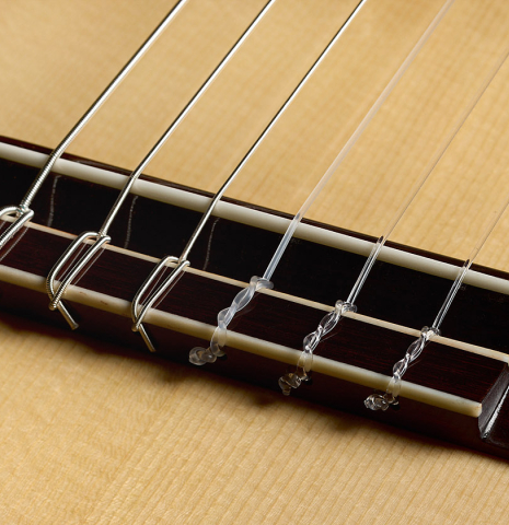 The bridge, tie-block and saddle of a 2026 Wolfgang Jellinghaus "Flamenca Negra" guitar made of spruce and African rosewood