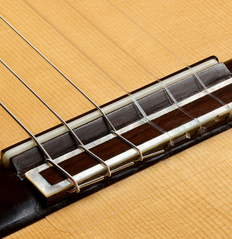 The bridge, tie-block and saddle of a 2014 Jose Marin Plazuelo "Negra" flamenco guitar made of spruce and Indian rosewood