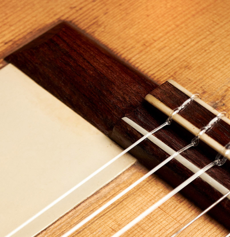 The bridge and saddle of a 1916 Viuda de Manuel Ramirez flamenco guitar made with spruce and cypress and pegs