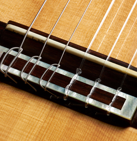 The bridge, tie-block and saddle of a 2003 Antonio Raya Pardo "Negra" flamenco guitar made of spruce and CSA rosewood