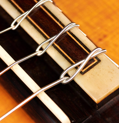 The bridge and saddle of a 1974 Manuel Reyes flamenco guitar made of spruce and cypress with traditional pegs