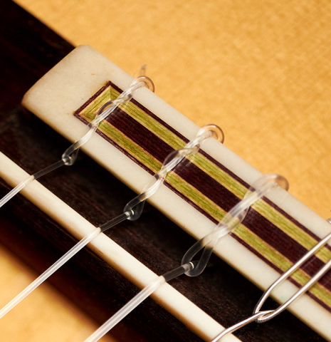 The bridge, saddle and nylon strings of a 2007 Manuel Reyes flamenco guitar made of spruce and cypress