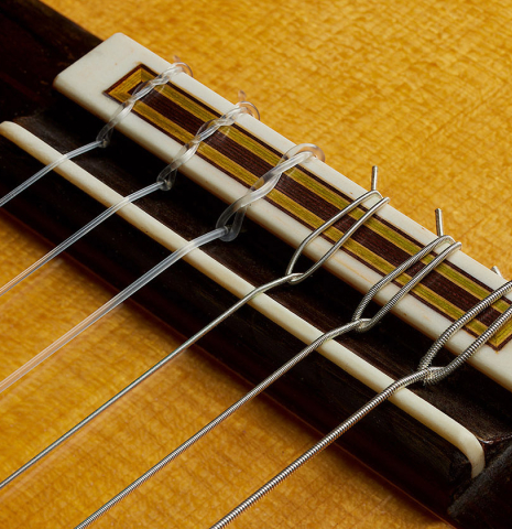 The bridge, tie-block and saddle of a 2003 Manuel Reyes "Negra" flamenco guitar made of spruce and CSA rosewood