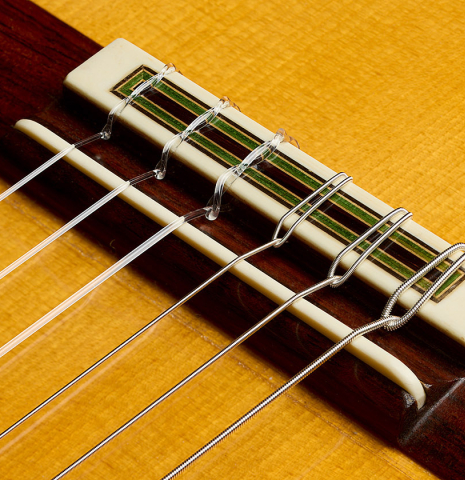 The bridge, tie-block and saddle of a 1992 Manuel Reyes flamenco blanca guitar made of spruce and cypress