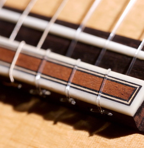 The bridge and saddle of a 2020 Pepe Romero &quot;Blanca&quot; flamenco guitar with traditional pegs made of spruce and cypress