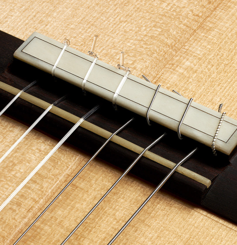 The bridge, tie-block and saddle of a 2024 Pepe Romero "Negra y Blanca" flamenco guitar made of spruce and CSA rosewood
