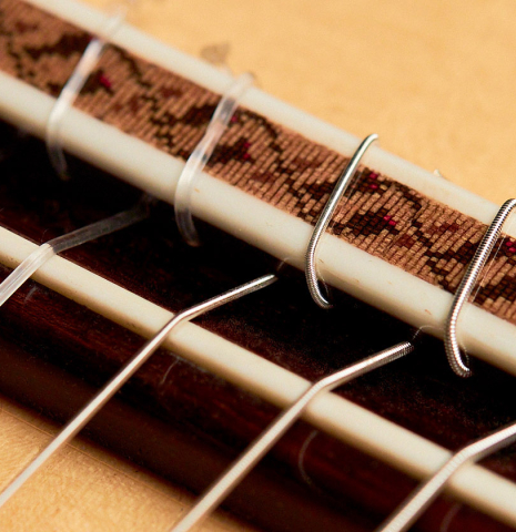 The ornamented bridge of a 2022 German Vazquez Rubio Concert Blanca Flamenco guitar made with spruce soundboard and cypress back and sides