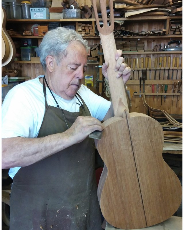 Manuel Bellido sanding the side of a classical guitar at his workbench